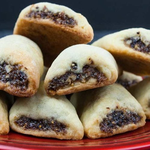 Italian fig cookies or Cucidati stacked on a red plate.