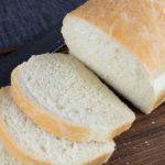 White bread sliced on a wooden cutting board.