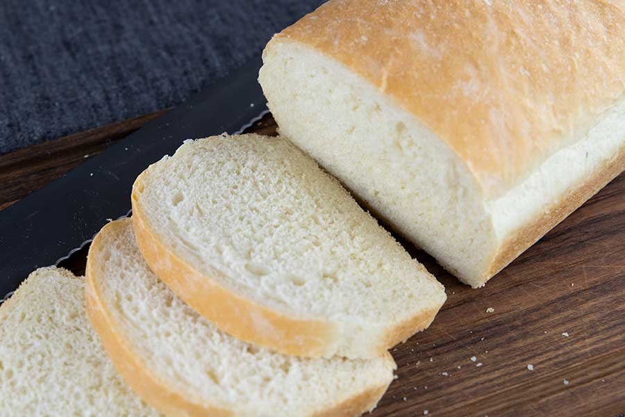 White bread sliced on a wooden cutting board.