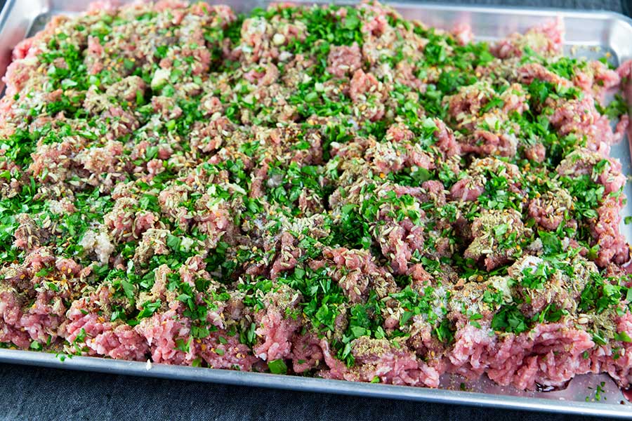 Ground pork sprinkled with the Italian sausage seasonings on a large baking sheet.