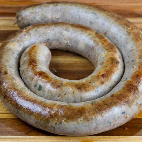 Cooked Italian sausage ring on a wooden cutting board.