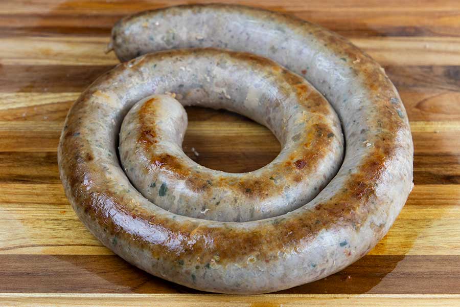 Cooked Italian sausage ring on a wooden cutting board.