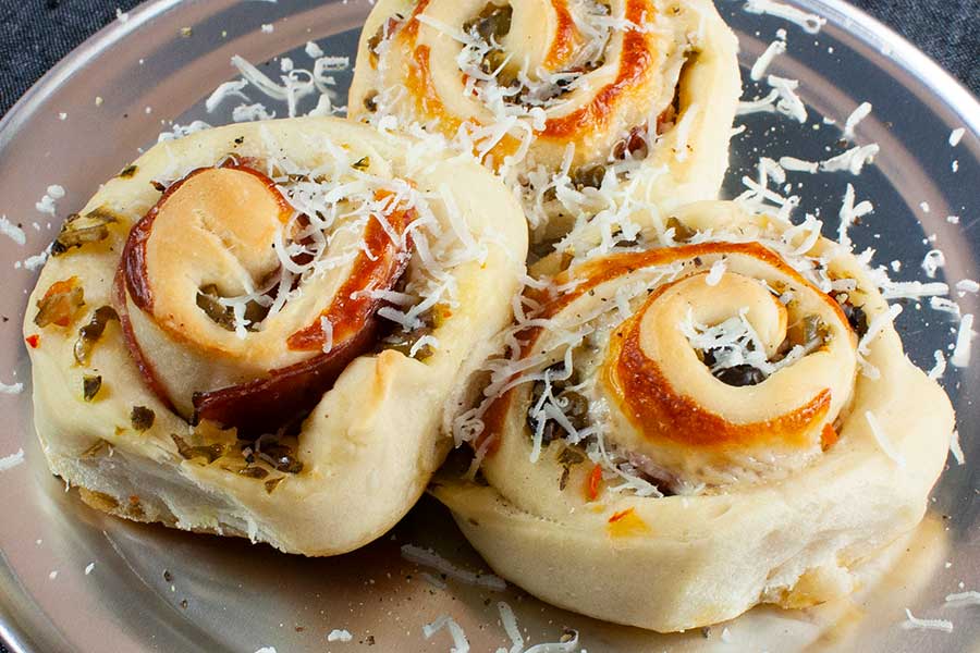 Muffuletta spirals on a silver plate garnished with parmesan cheese.