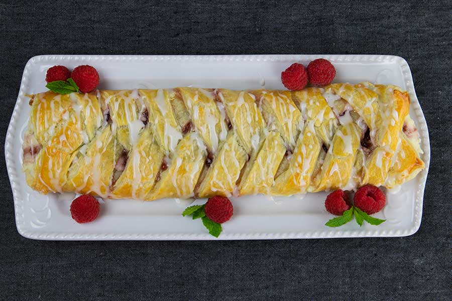 Raspberry Cream Cheese Danish - baked danish on a white serving dish garnished with fresh raspberries and mint