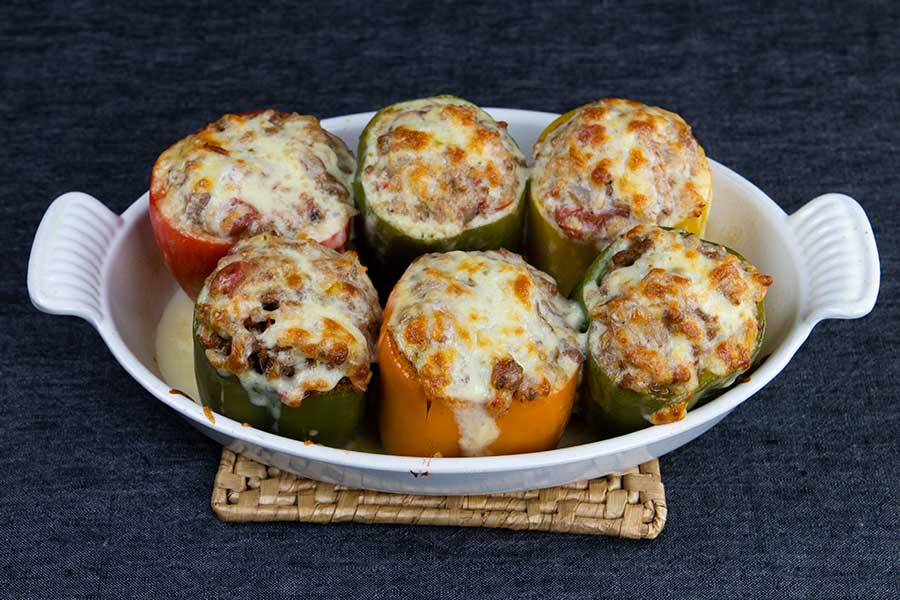 Cooked stuffed bell peppers in a white baking dish just removed from the oven.