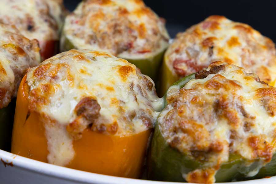 A close up of stuffed bell peppers with melted cheese on top.