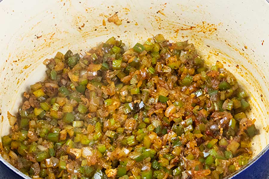 Diced vegetables cooking in a large dutch oven.