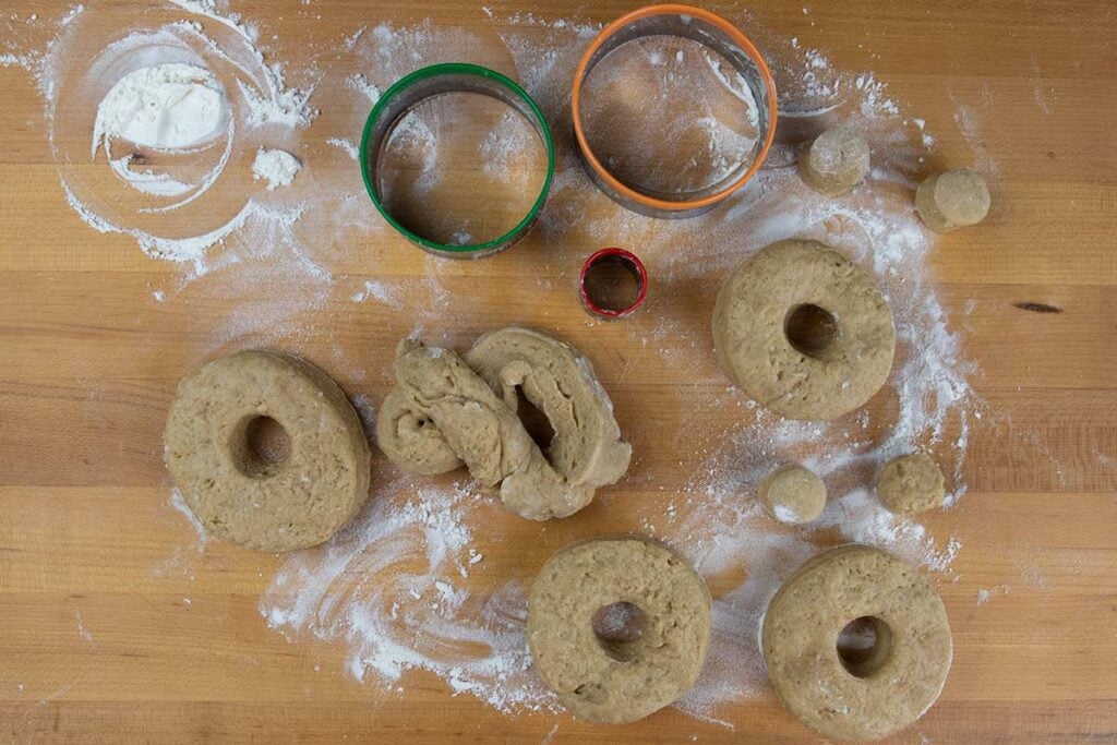 Apple cider donut dough cut out on wooden board.