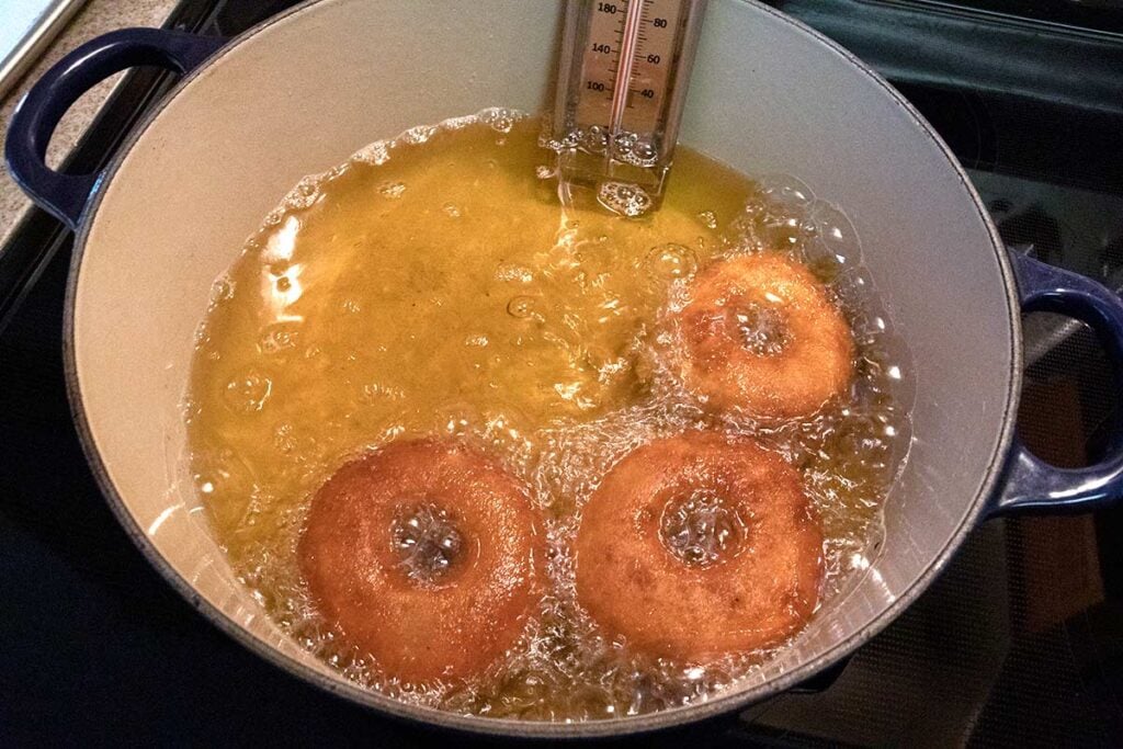 Apple cider donuts frying in a dutch oven.