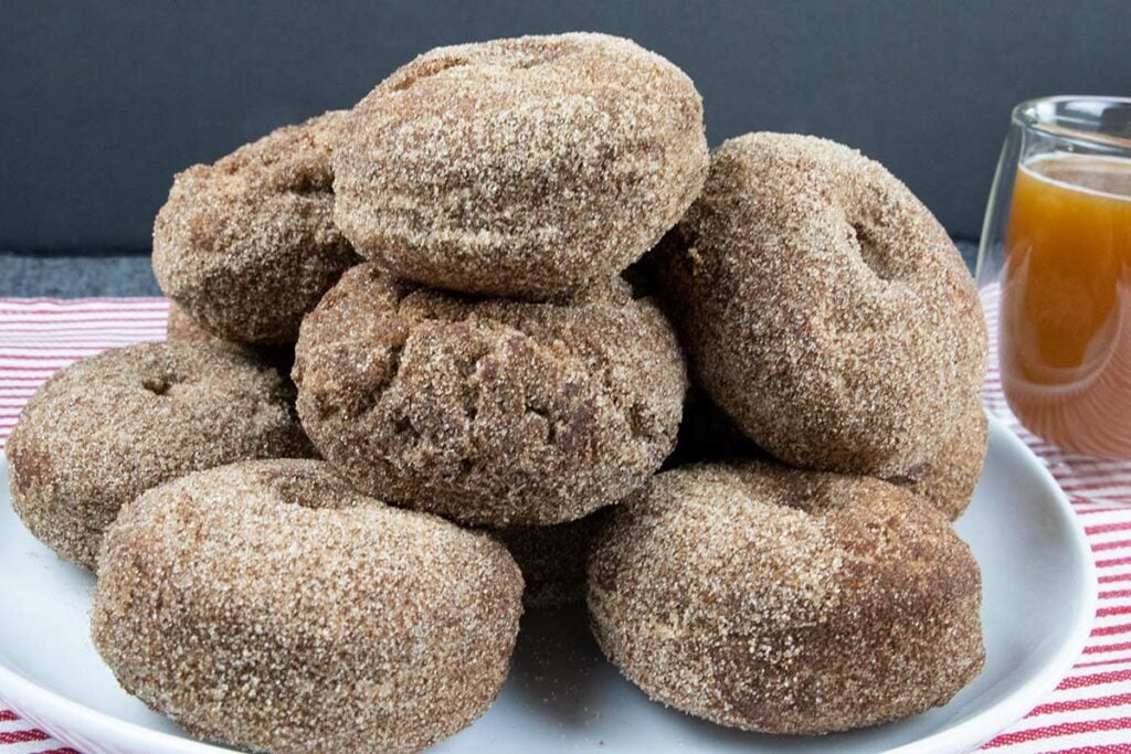 Apple cider donuts stacked on a white plate.