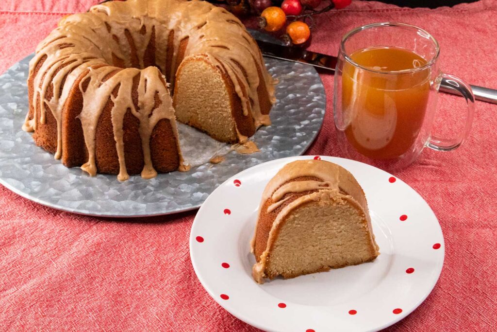 Apple cider pound cake with one slice on a white plate.