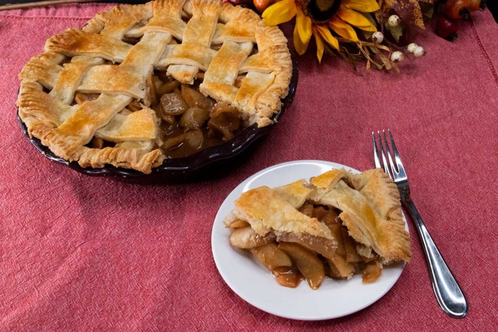 Slice of apple pie on white plate.