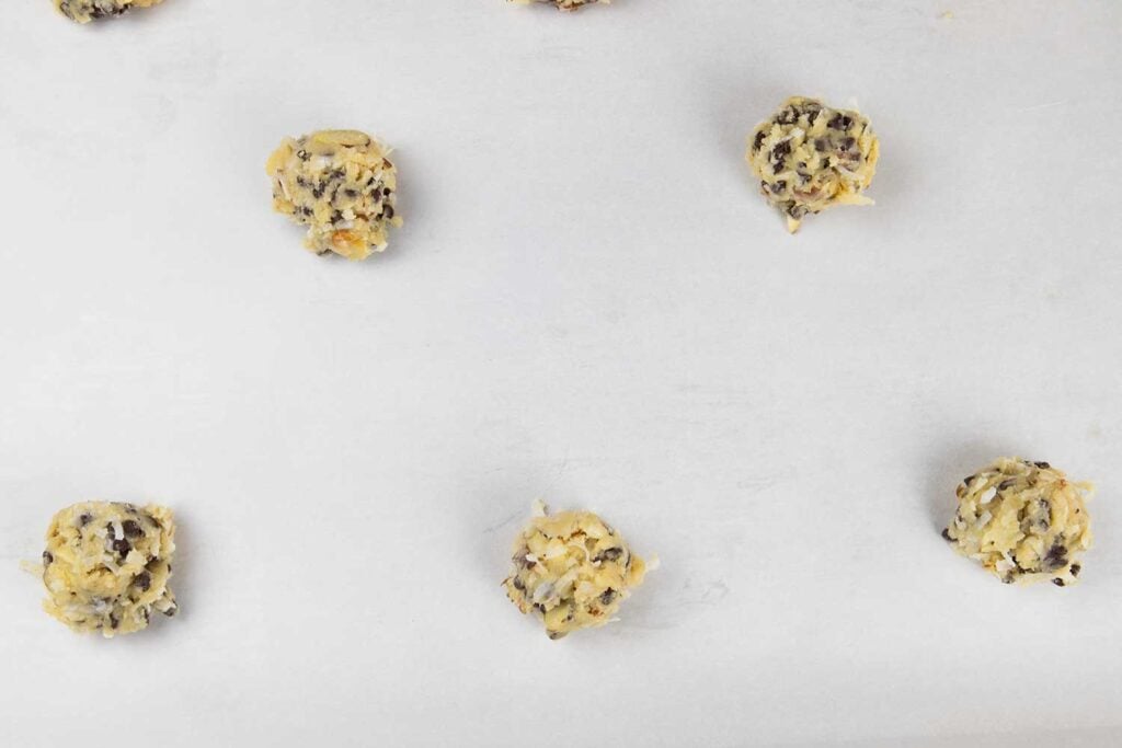 Cookie dough balls on parchment lined baking sheet.