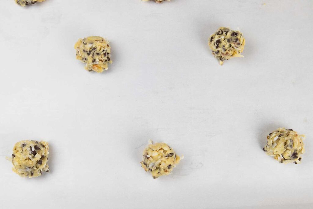 Cookie dough balls on parchment lined baking sheet.