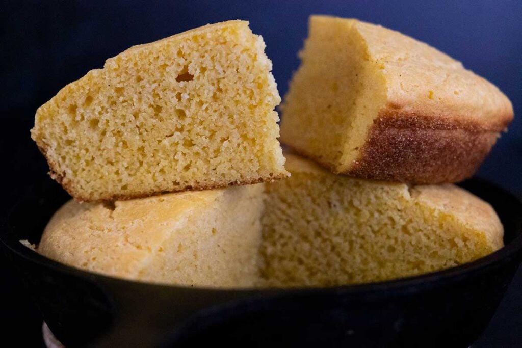 Slices of buttermilk cornbread stacked in a cast iron skillet.