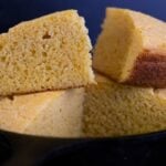 Slices of buttermilk cornbread stacked in a cast iron skillet.