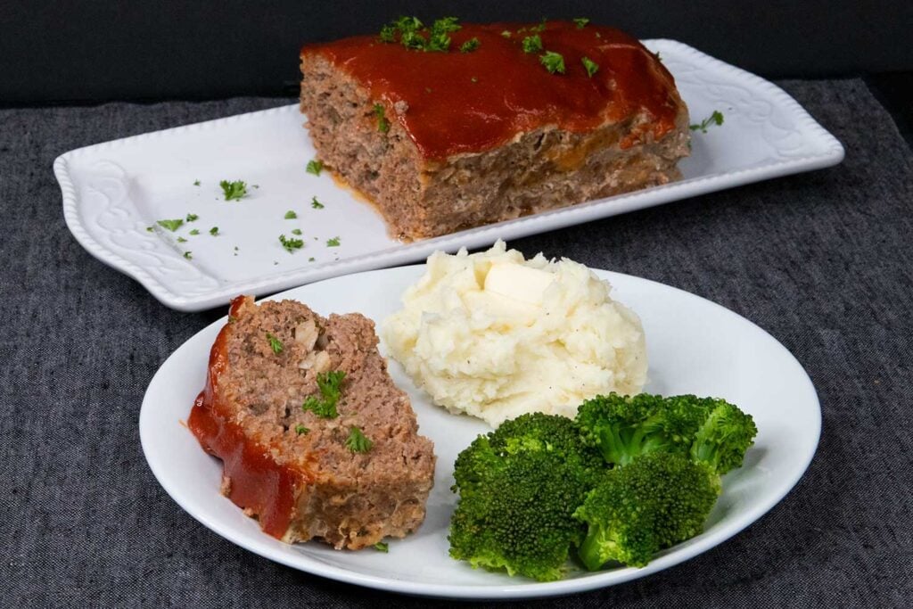 Meatloaf with mashed potatoes and broccoli on a white plate.