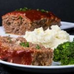 Meatloaf with mashed potatoes and broccoli on a white plate.