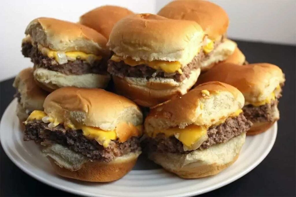 Oven Baked Sliders stacked up on a white plate.