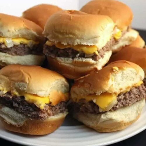 Oven Baked Sliders stacked up on a white plate.