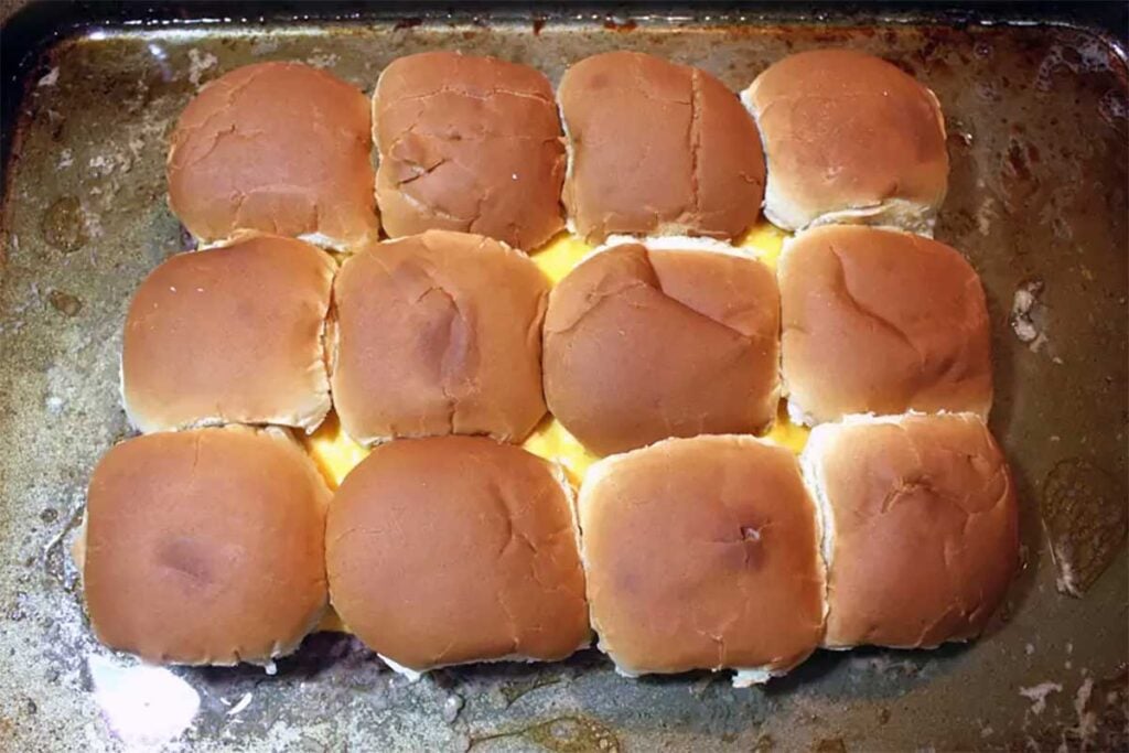 oven baked sliders on baking sheet with bun tops placed on top