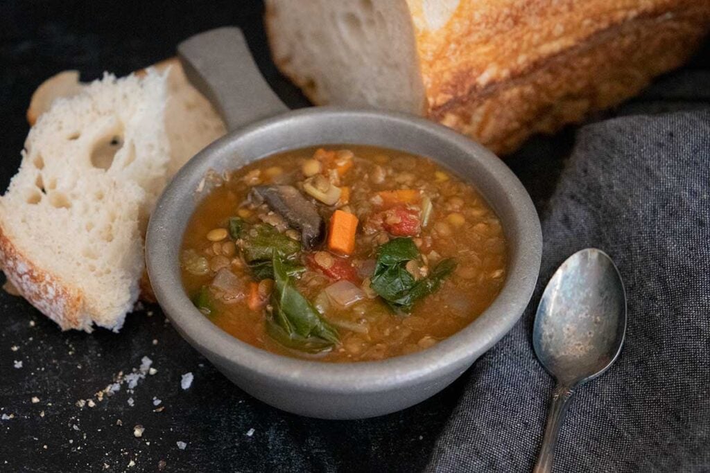 Slow cooker lentil soup with a loaf of bread.