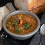 Slow cooker lentil soup with a loaf of bread.