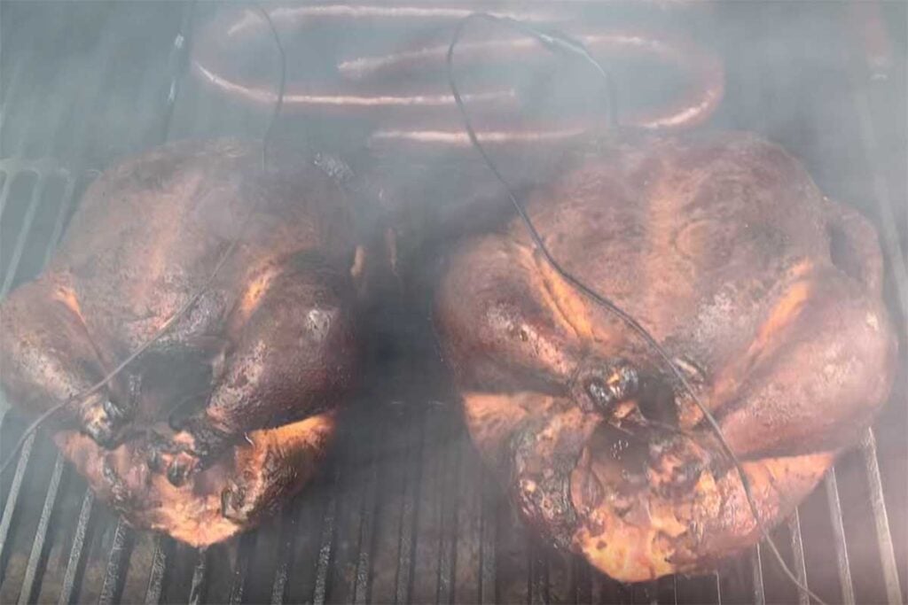 Two smoked chickens in the smoker with sausage.