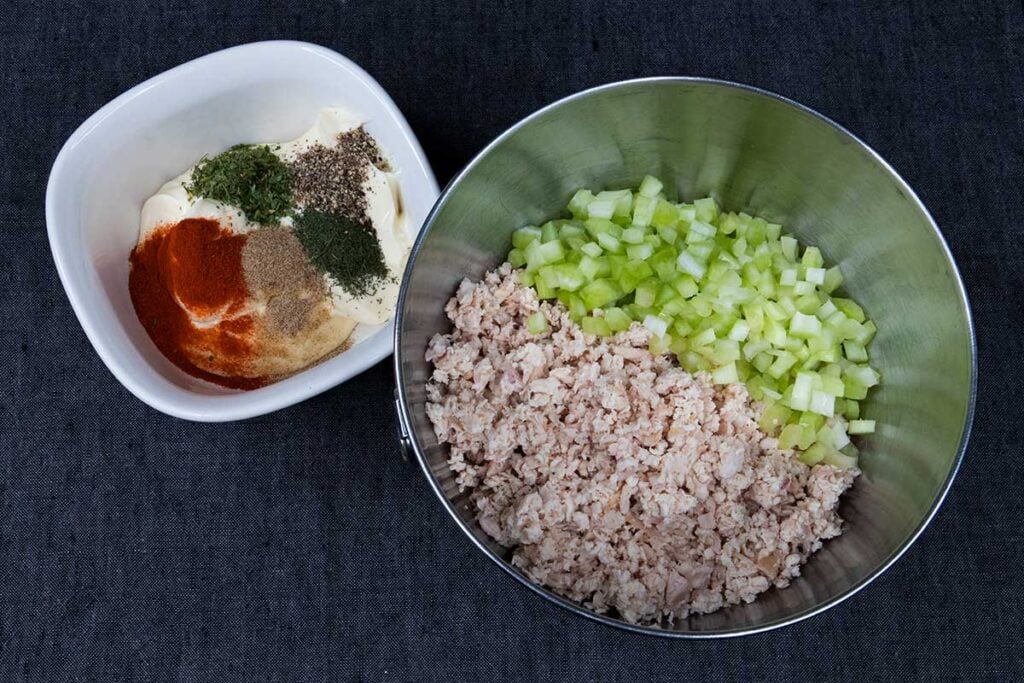 Minced smoked chicken and diced celery in a metal bowl.