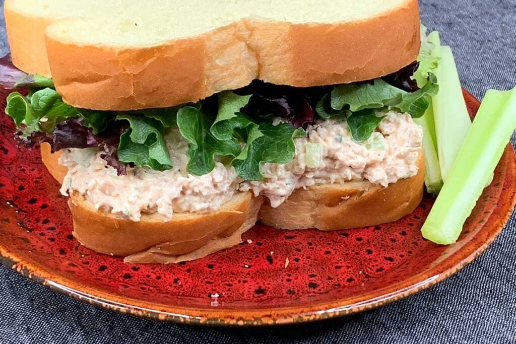 Smoked chicken salad sandwich on a red plate.