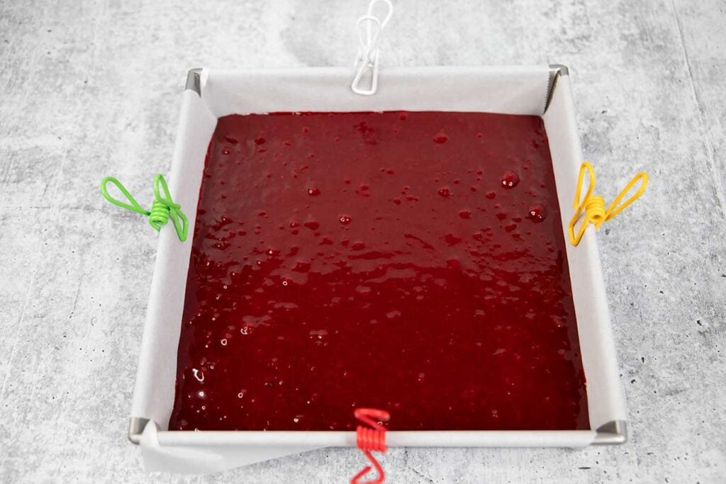 Red velvet brownie batter in a metal pan lined with parchment paper.