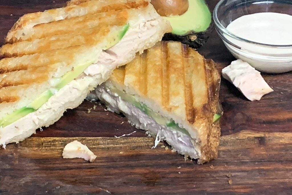 Smoked chicken panini sandwich on a cutting board.