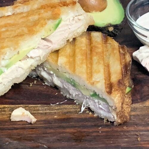 Smoked chicken panini sandwich on a cutting board.