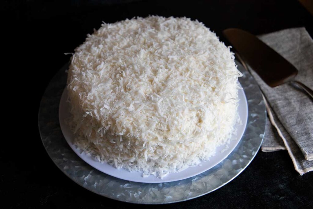 Coconut cake on a metal platter.
