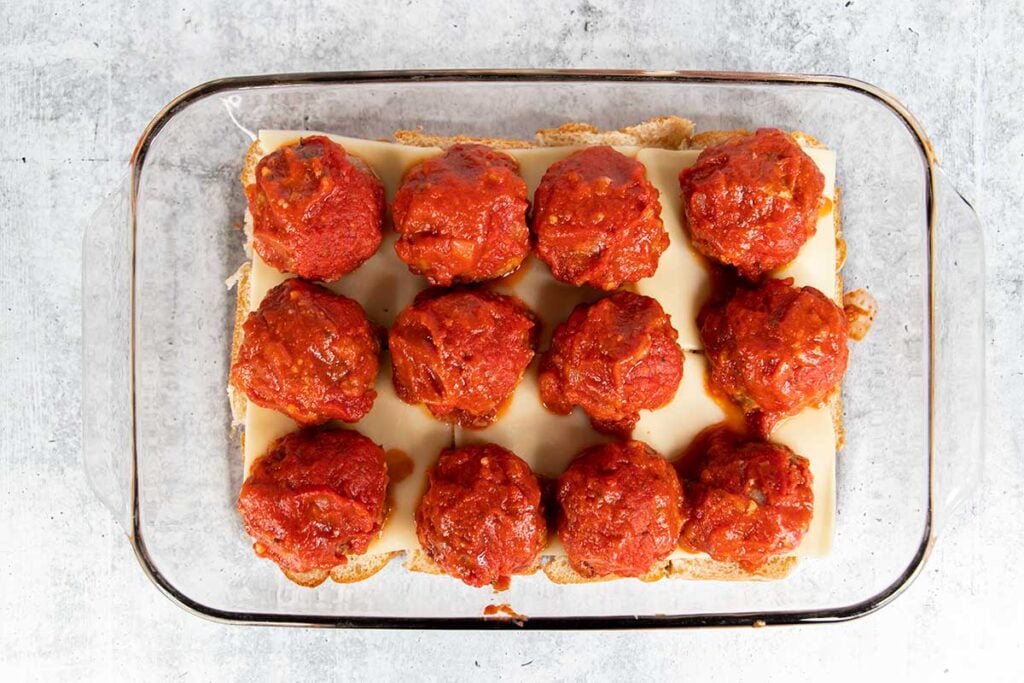 Meatballs topped with marinara on the bottom buns.