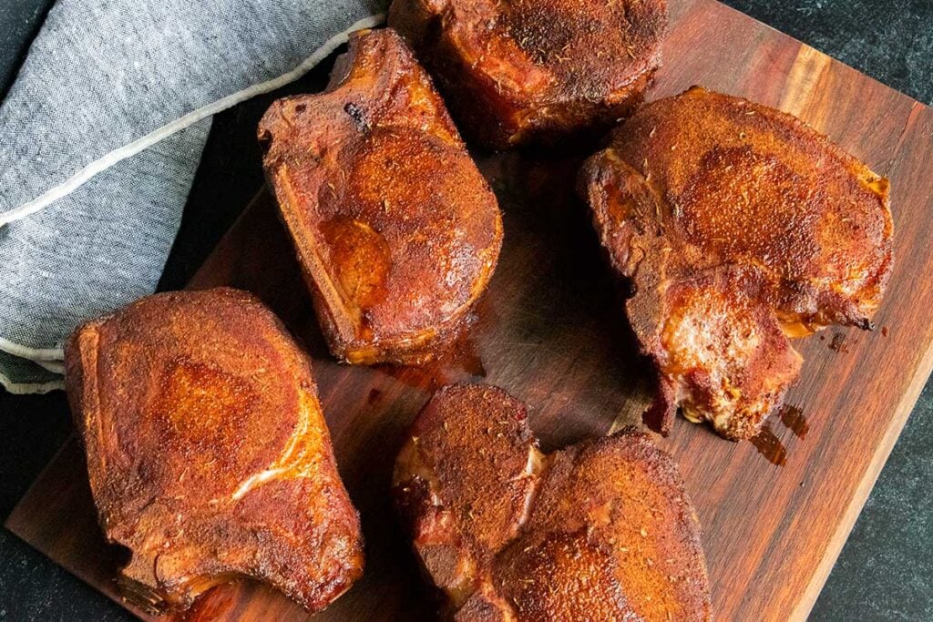 Smoked double bone-in pork chops resting on a cutting board.