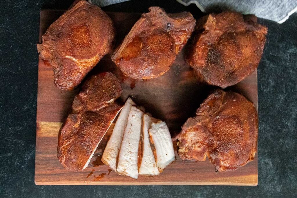 Double bone-in smoked pork chops on a cutting board with slices of meat showing