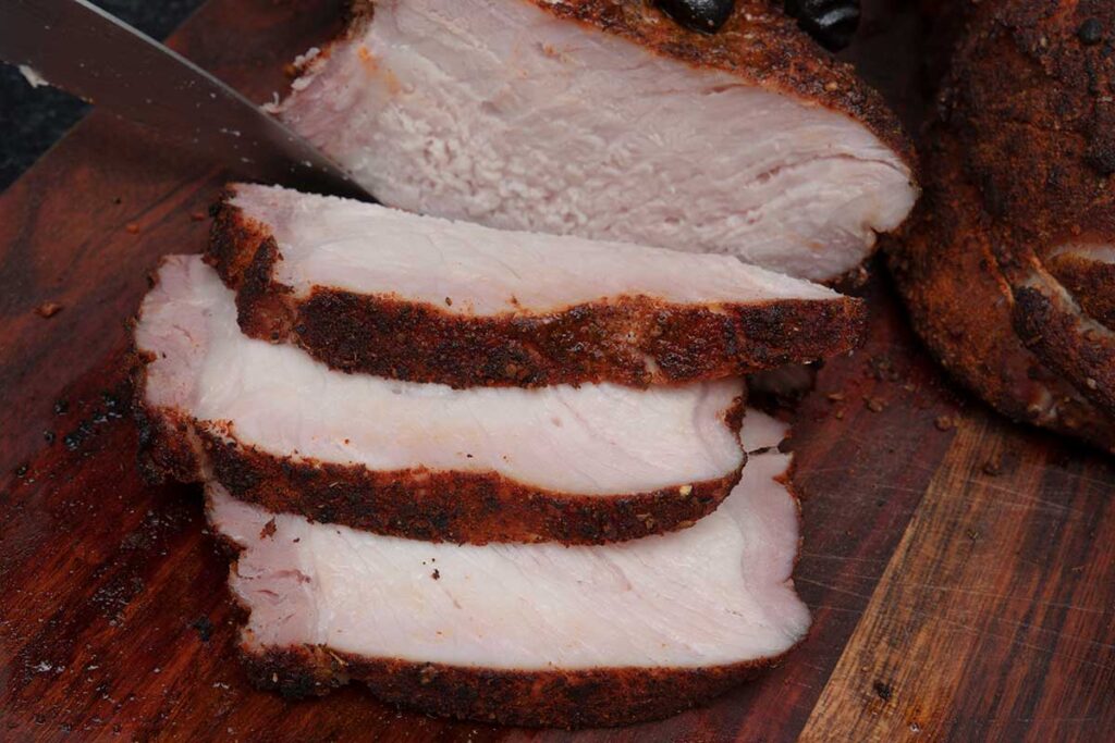 Slices of double bone-in smoked pork chops on a cutting board.