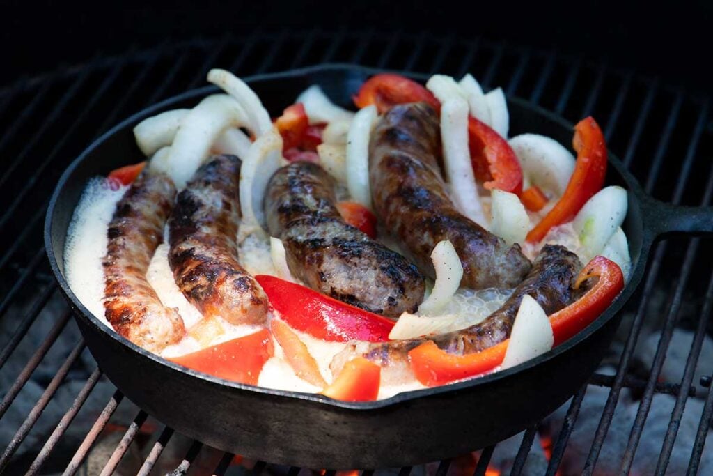 Beer brats with onions and peppers on the grill
