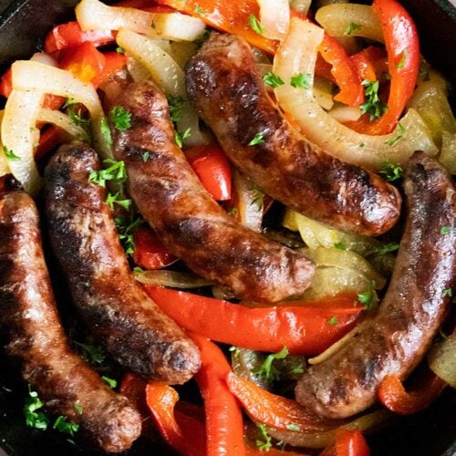 Beer brats with peppers and onions in a cast iron skillet.