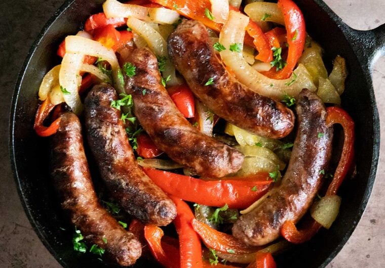beer brats with peppers and onions in a cast iron skillet