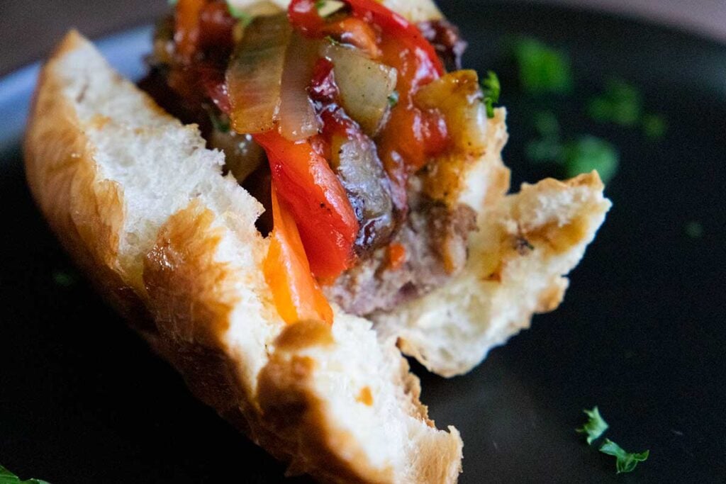 A half eaten beer brat on a black plate