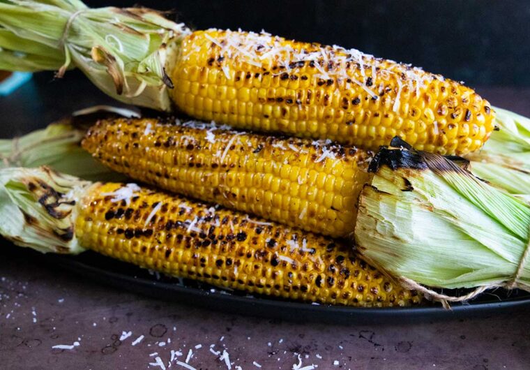 Grilled corn on the cob on a black plate