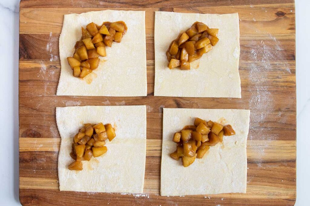 Puff pastry cut into squares with apple filling in the middle.