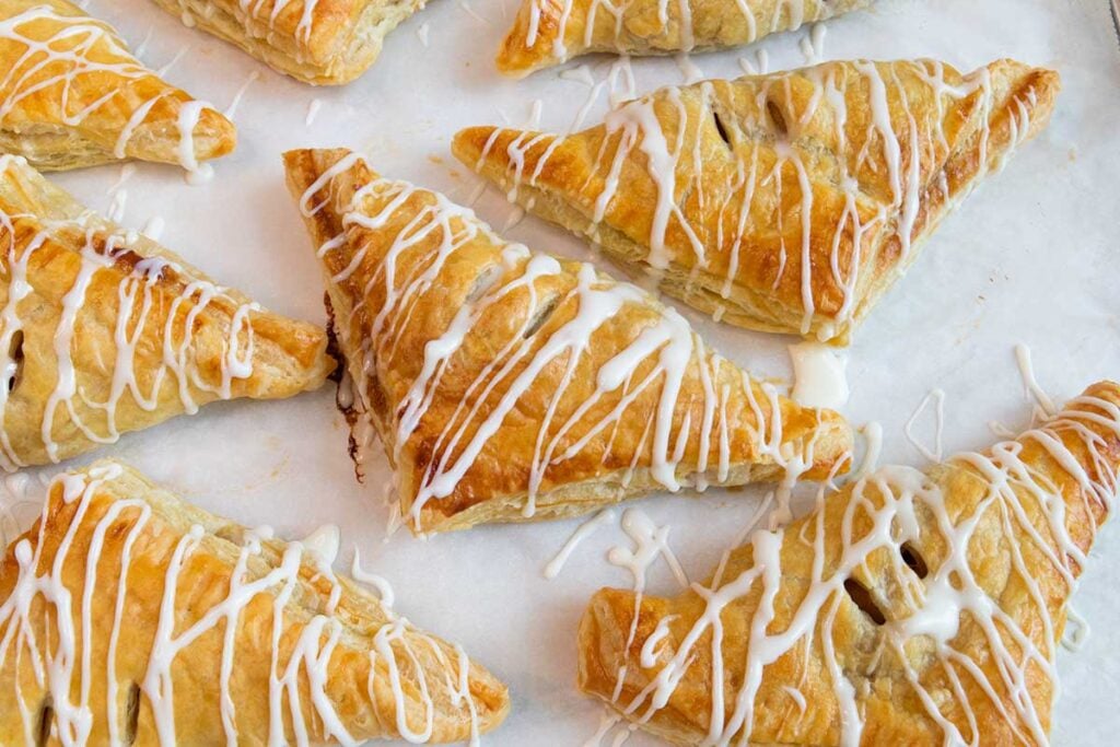 Glazed apple turnovers on a baking sheet.