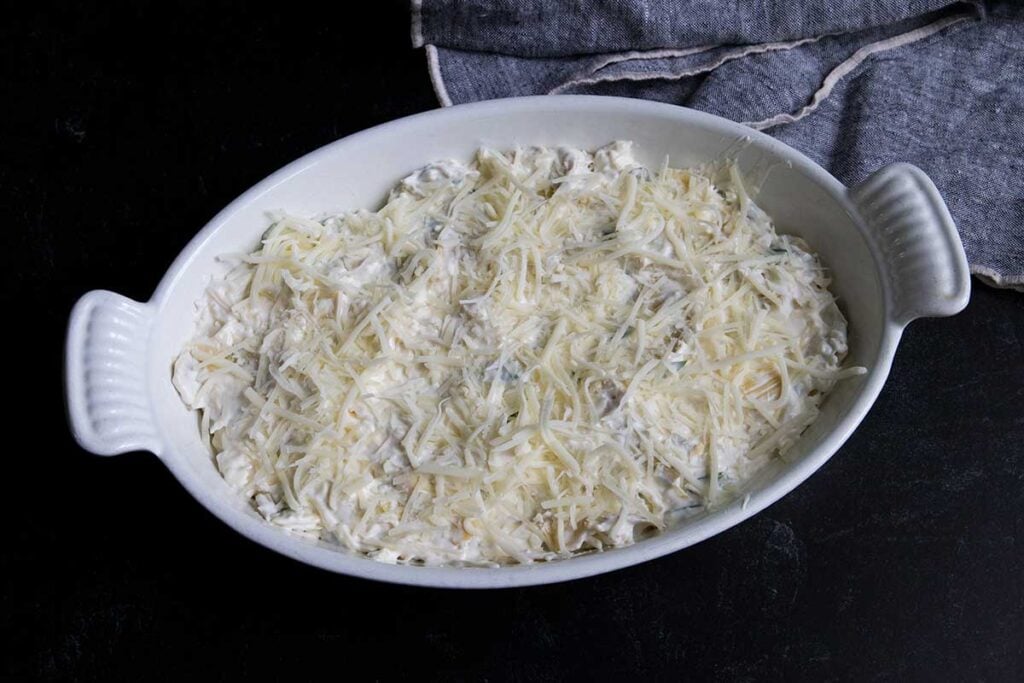 Unbaked artichoke dip mixture in a white casserole dish.