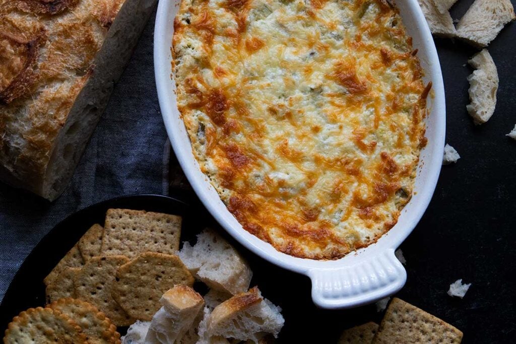 Artichoke dip in a white baking pan.