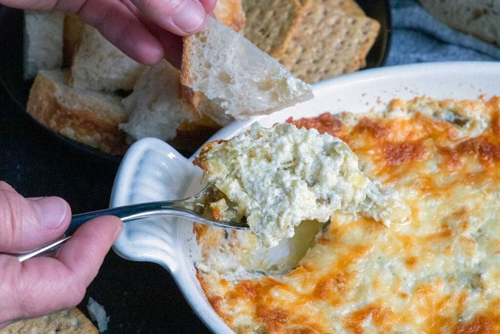 Artichoke dip scooped in a spoon.