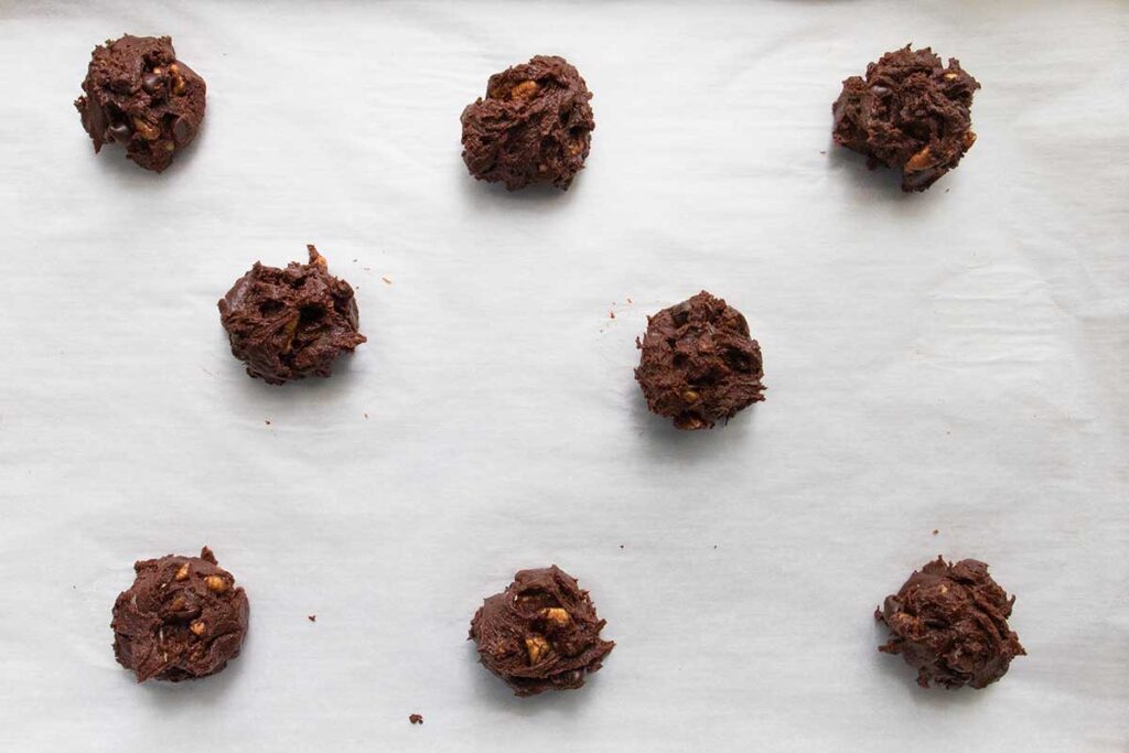 Brownie cookie dough balls on a parchment lined baking sheet.