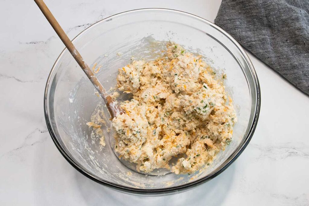 Cheddar chive biscuit dough in a glass mixing bowl.